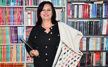 Omzuna astığı çantasındaki kitapları öğrencilere ulaştırıyor